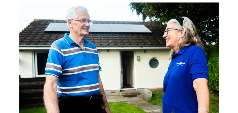 Tom Kingdom smiling outside of his home with new solar panels. 