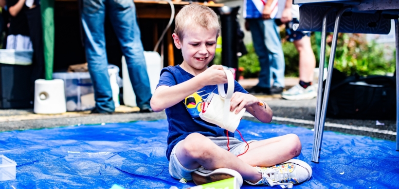 A boy sat on the floor making something with materials. 