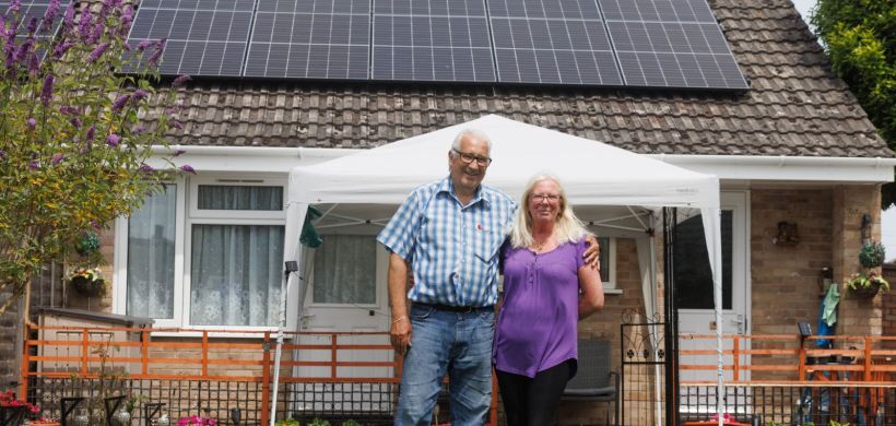 Malcolm and Michelle standing outside of their home with solar panels