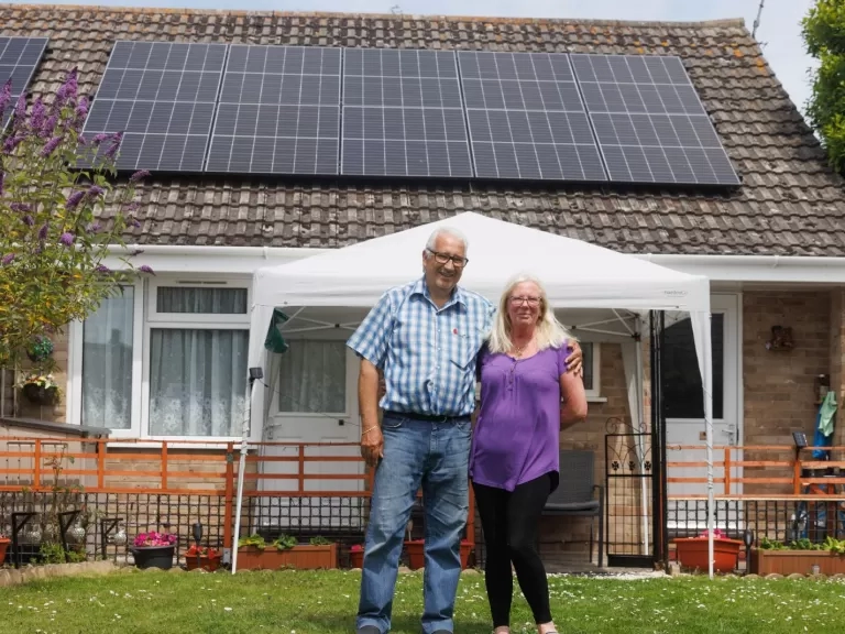 Malcolm and Michelle standing outside of their home with solar panels