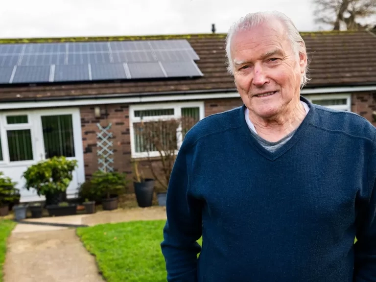 Patrick smiling outside his home with new solar panels.