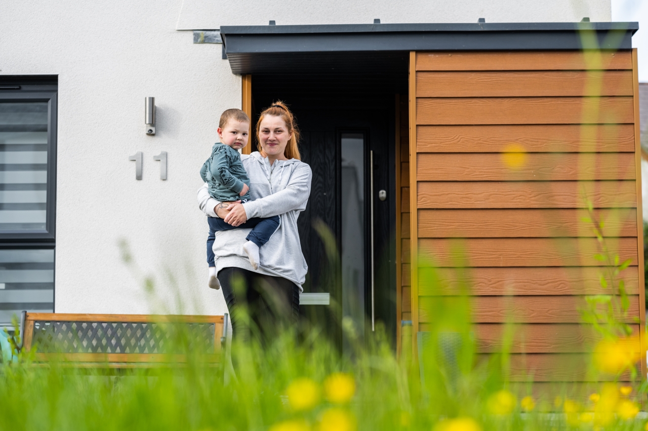 Woman with child outside a house.