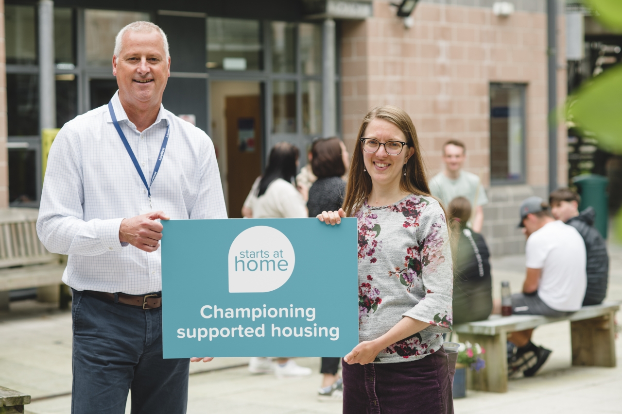 People holding a sign saying 'championing supported housing'.