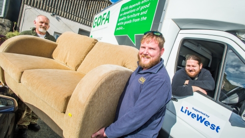 Men smiling and carrying a sofa